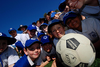 School kids huddled around a soccer ball